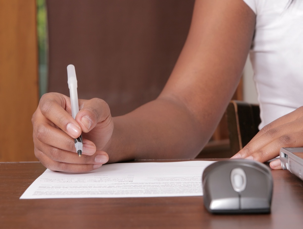 woman writing on a piece of paper near a workstation