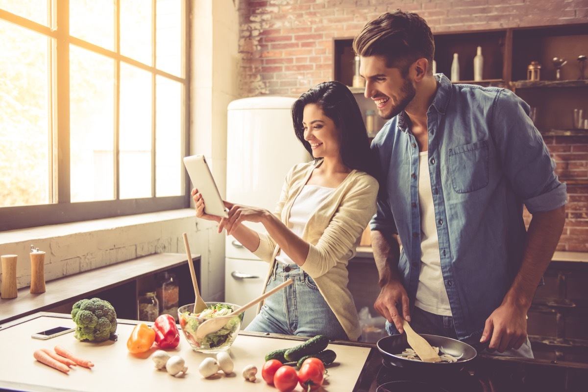 Attractive young couple cooking healthy meal in their kitchen