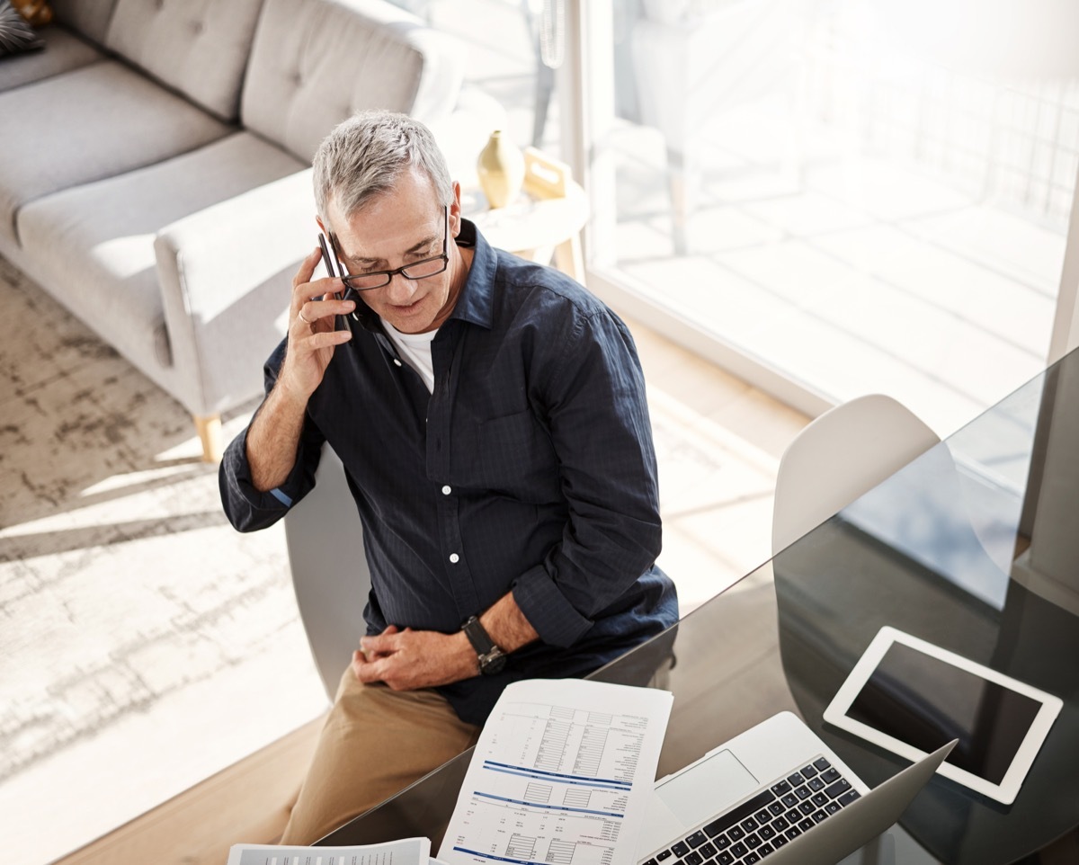 High angle shot of a mature man talking on a cellphone at home