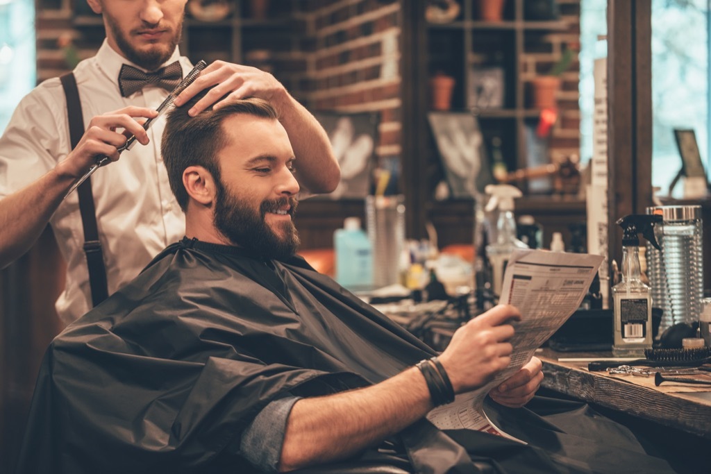 a man getting a haircut in a barber shop