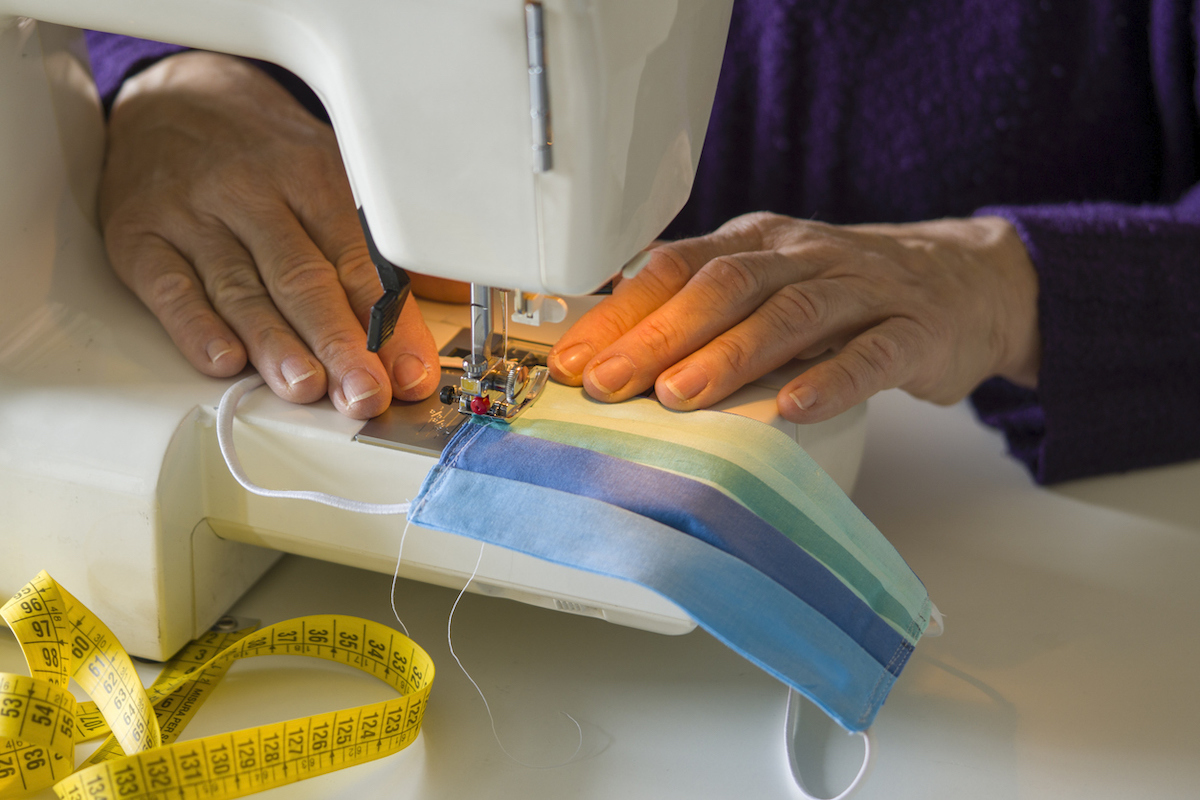 hands preparing a blue mask on a sewing machine to protect from Covid-19 viral effect.