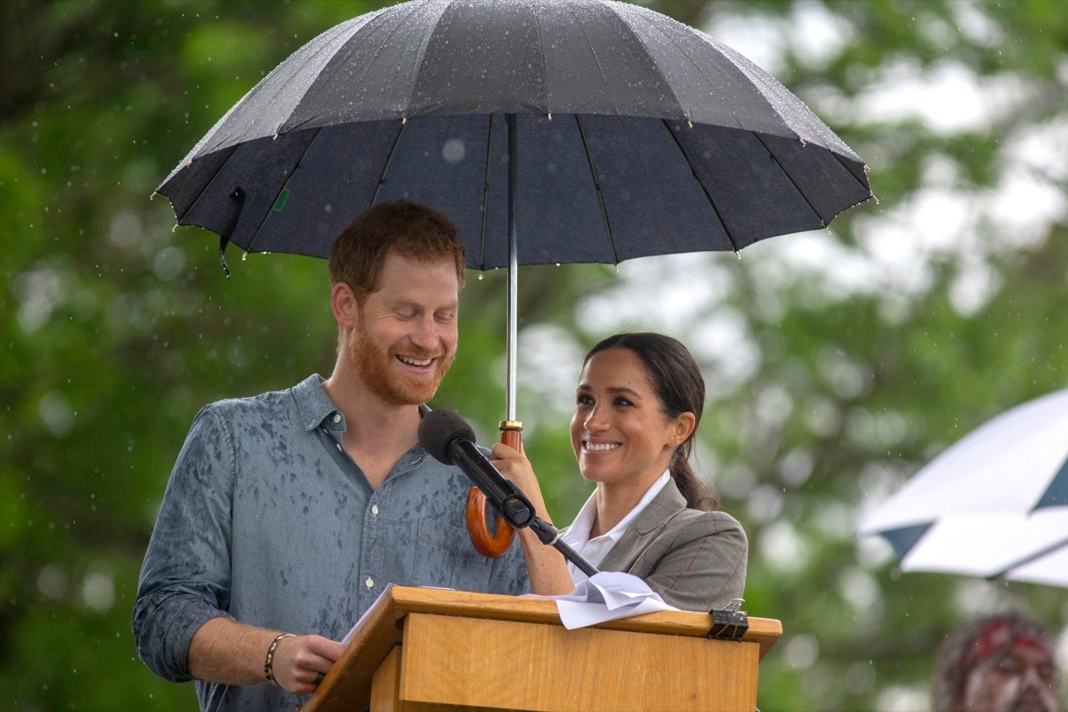 The Duchess of Sussex holds an umbrella as the Duke of Sussex makes a speech at a community picnic in Victoria Park in Dubbo, New South Wales, on the second day of the royal couple's visit to Australia.