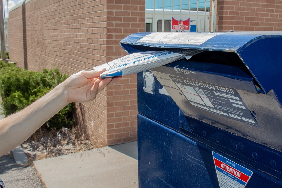 hand putting package into mailbox