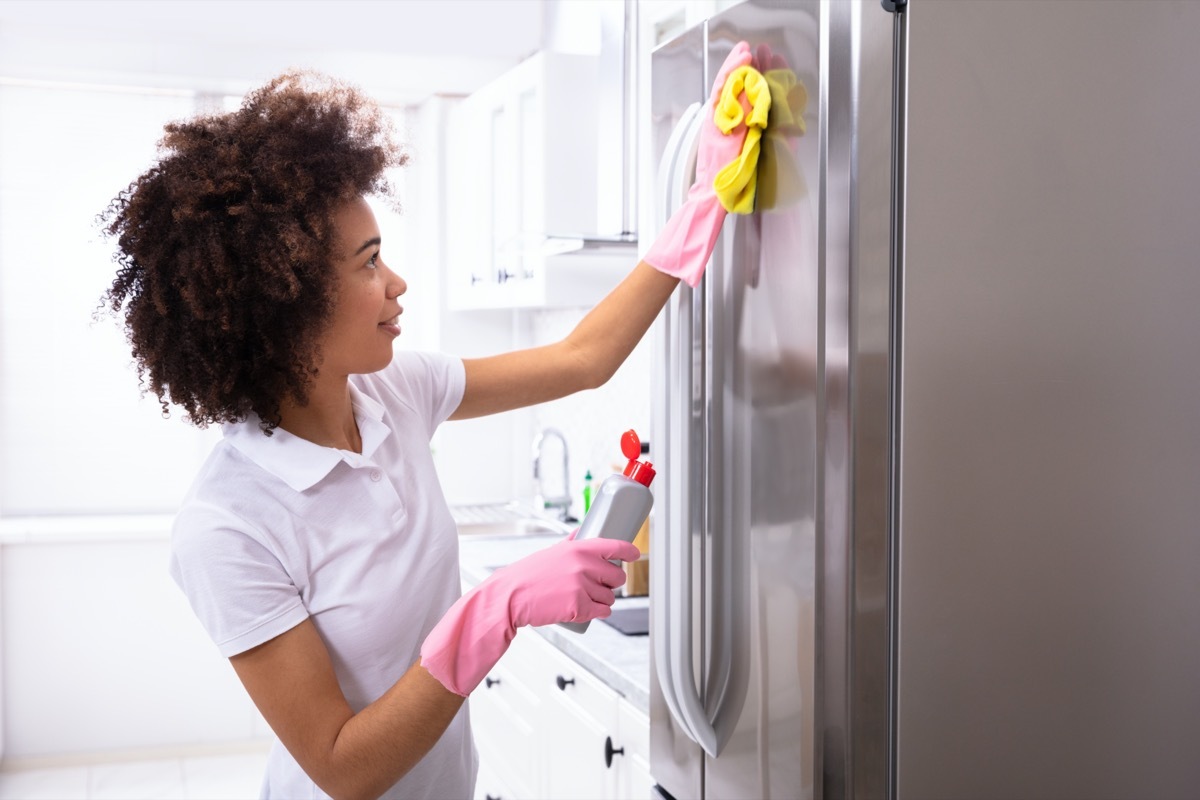 Woman cleaning fridge with gloves