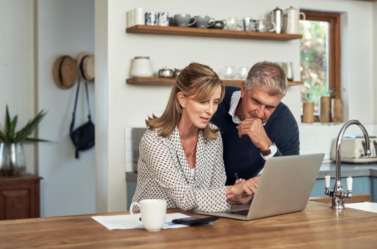 A senior couple planning their finance and paying bills while using a laptop at home.