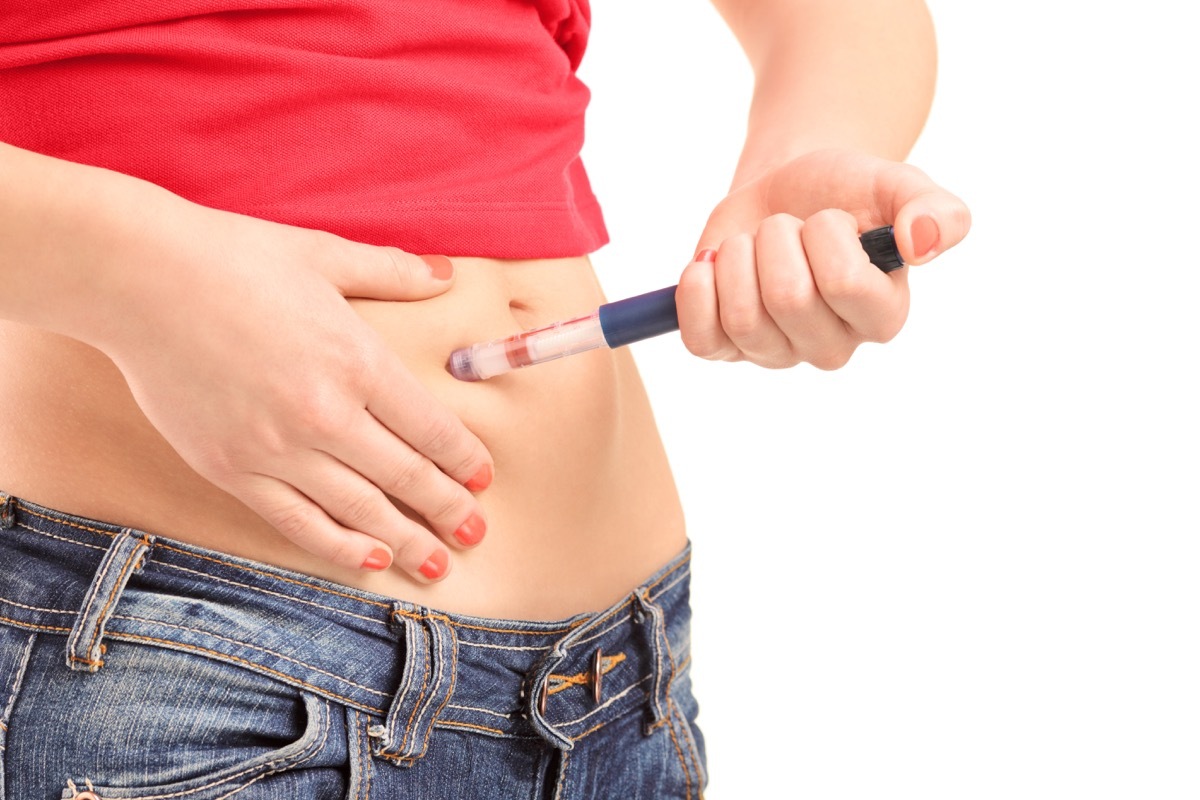 Young female injecting her abdomen isolated on white background 