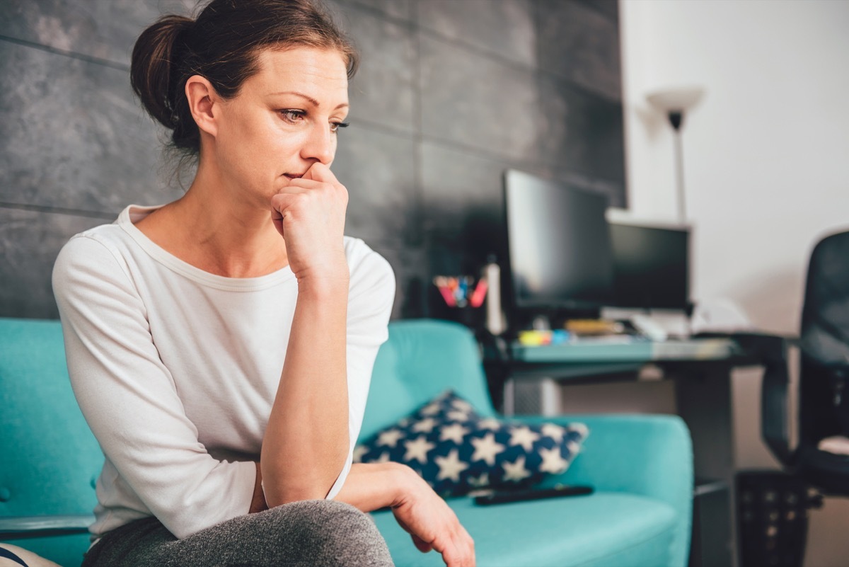 sad white woman sitting on the couch in a living room