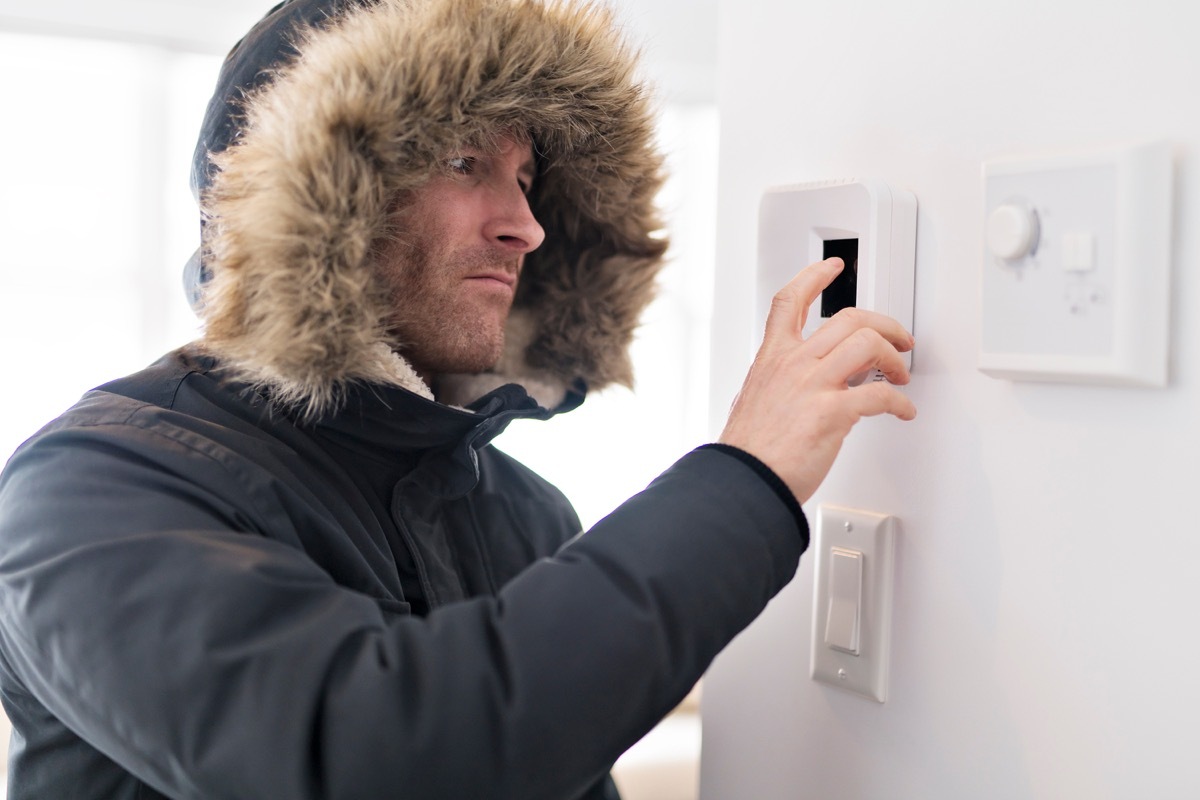 man whose cold wearing a jacket and turning up the temperature 