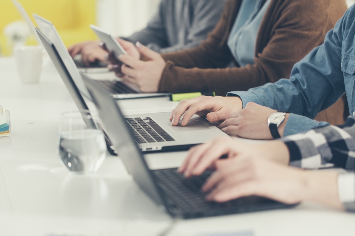 abstract photo of multiple people's hands typing on a laptop