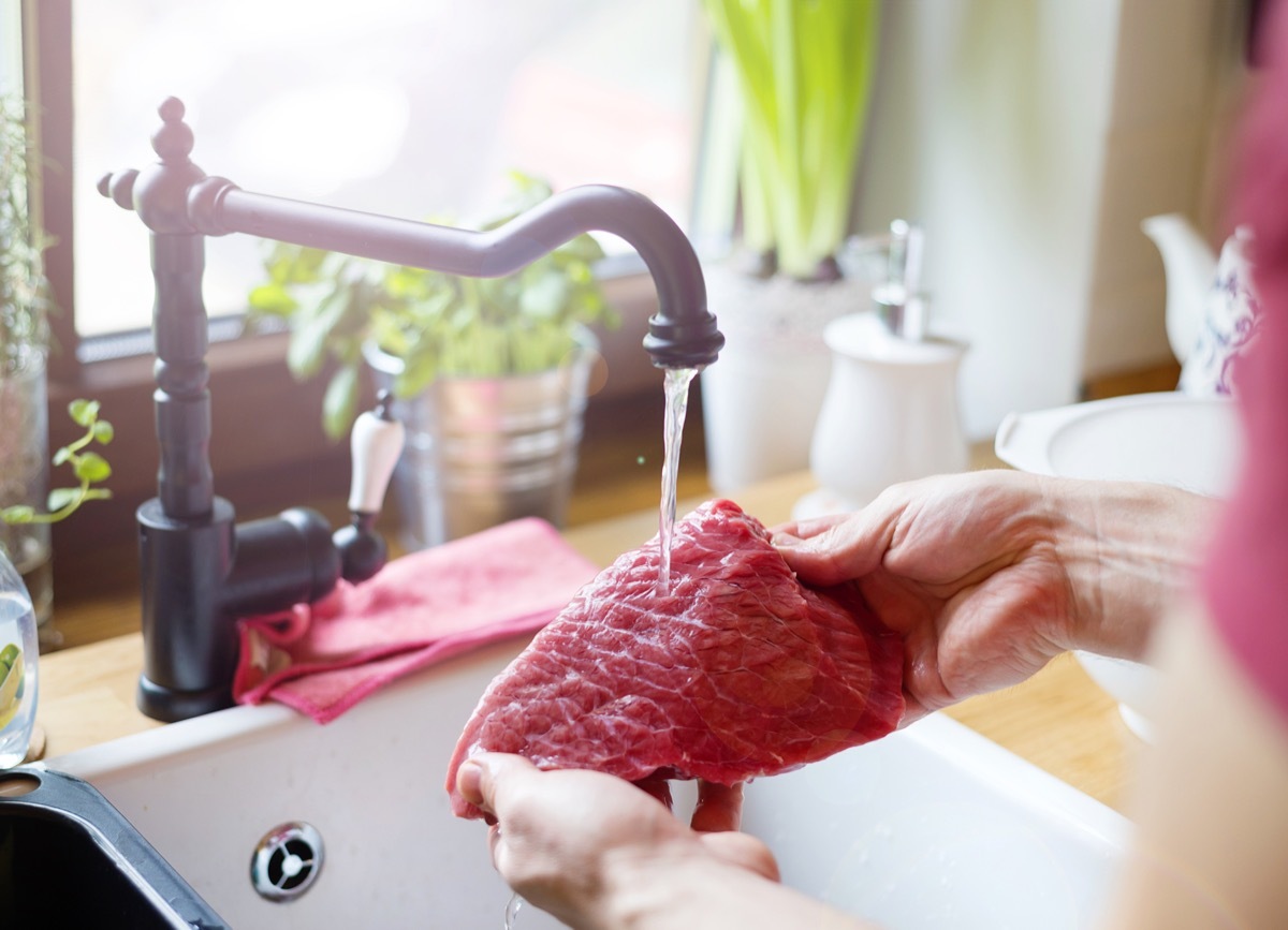 Man washing meat in sink