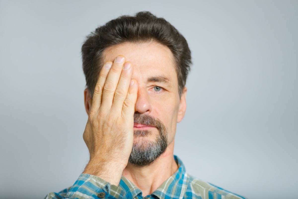 middle-aged man covers eyes with hands, does not see,