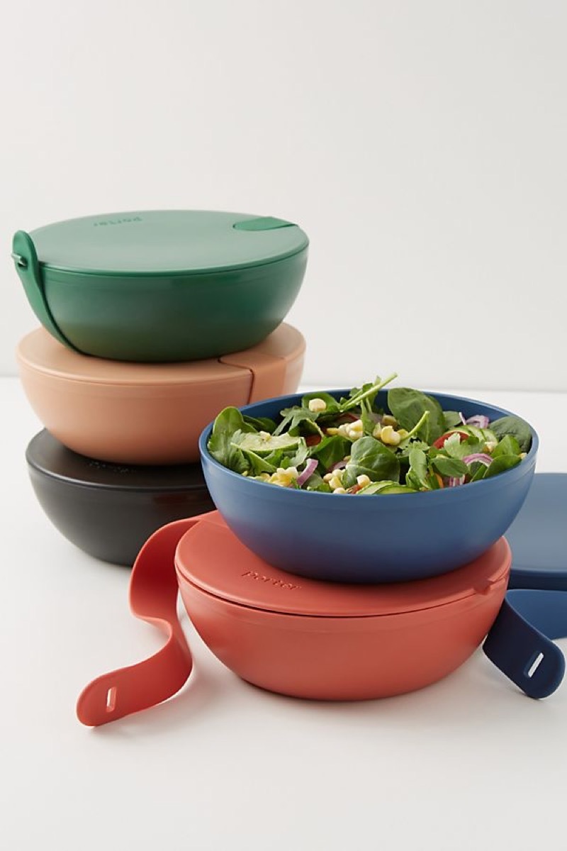 five bowls in different colors, one with salad greens in it