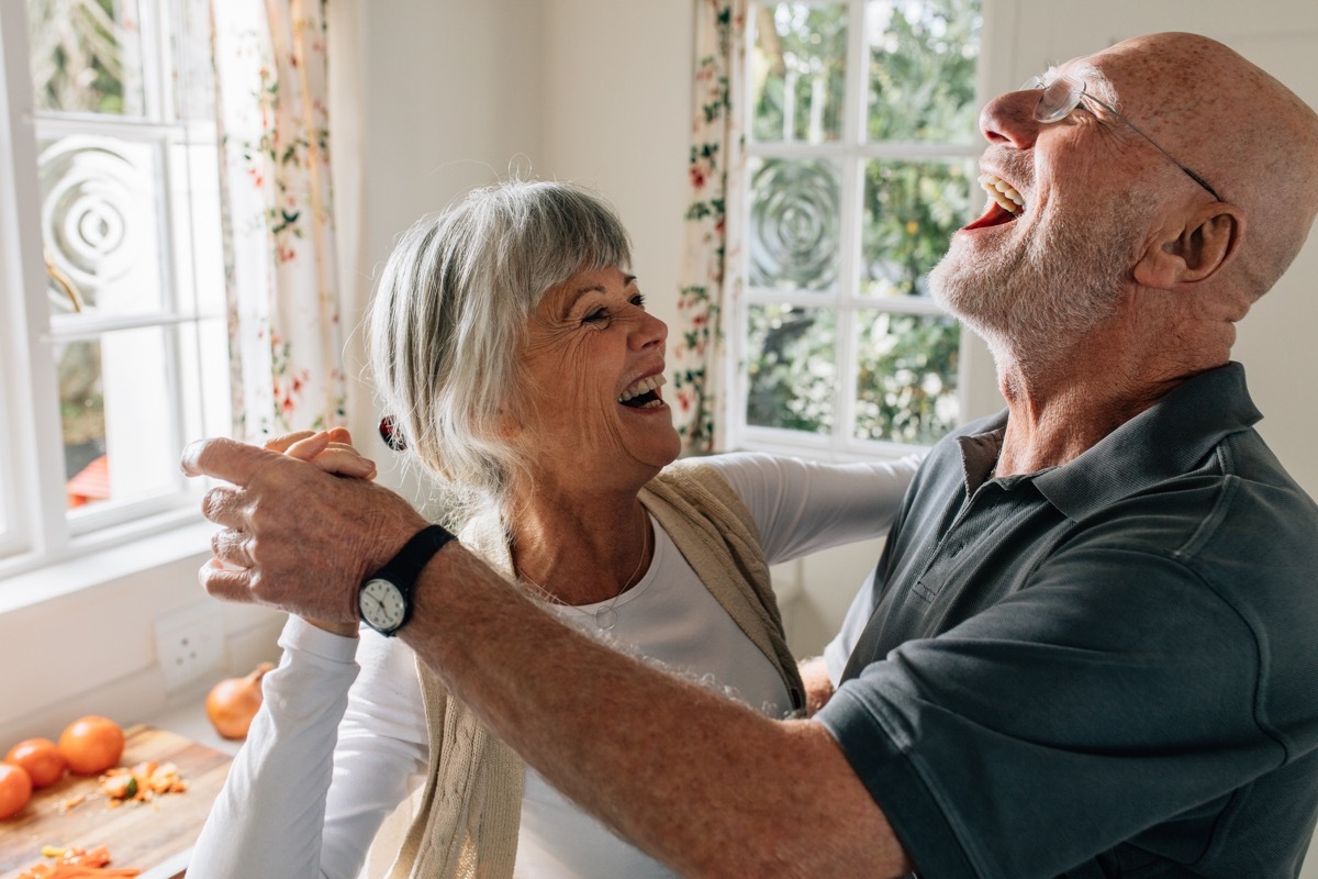 Senior man and woman dancing at home.