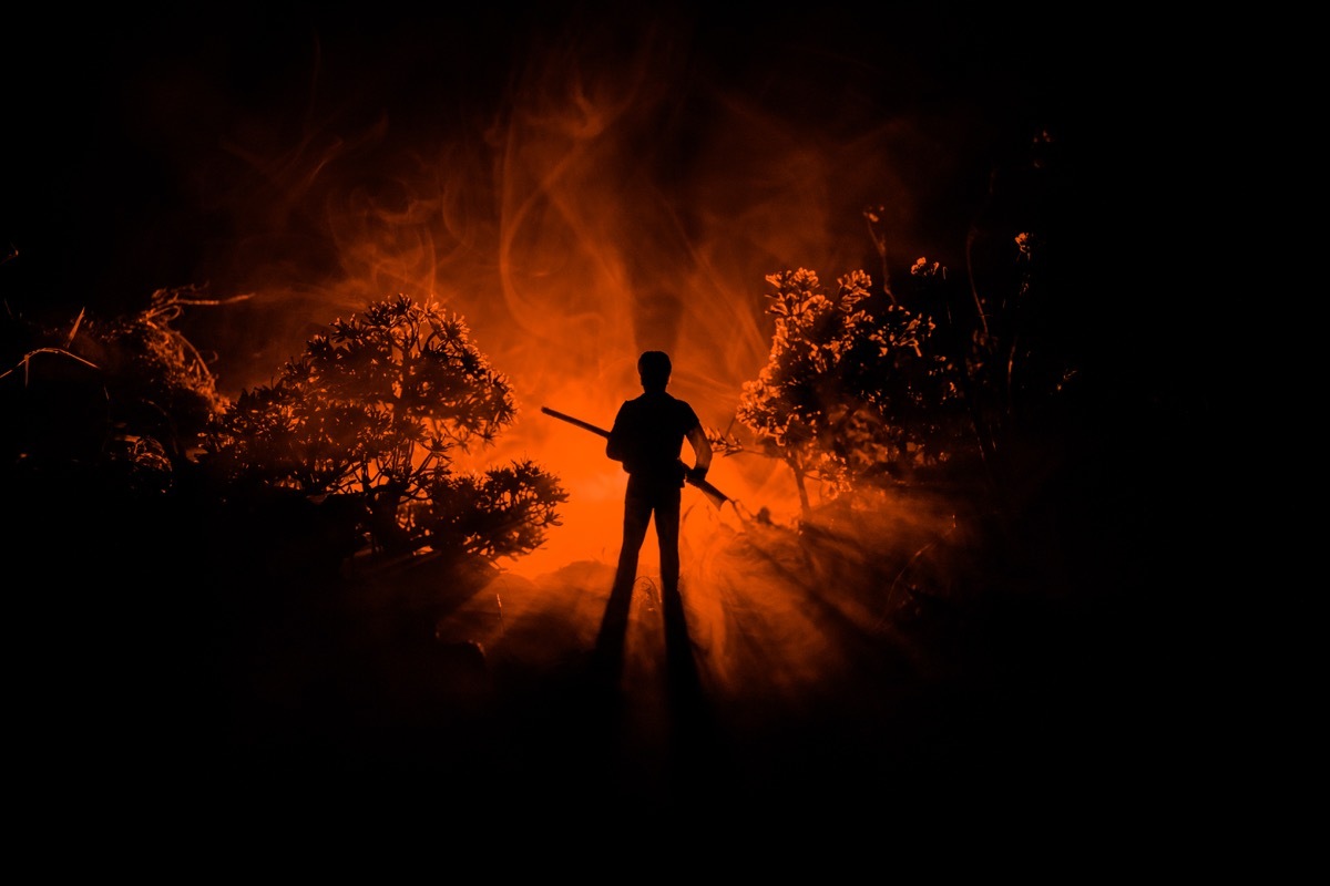 man with a rifle in front of a red background