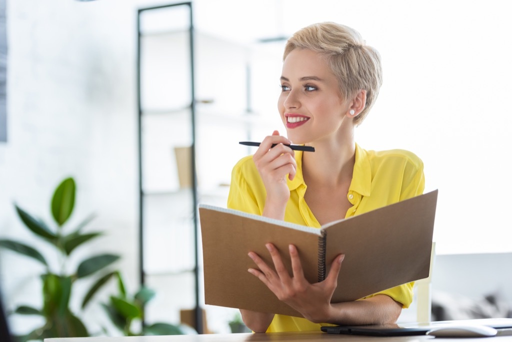 Woman is smiling at her notebook because she's proud of herself.