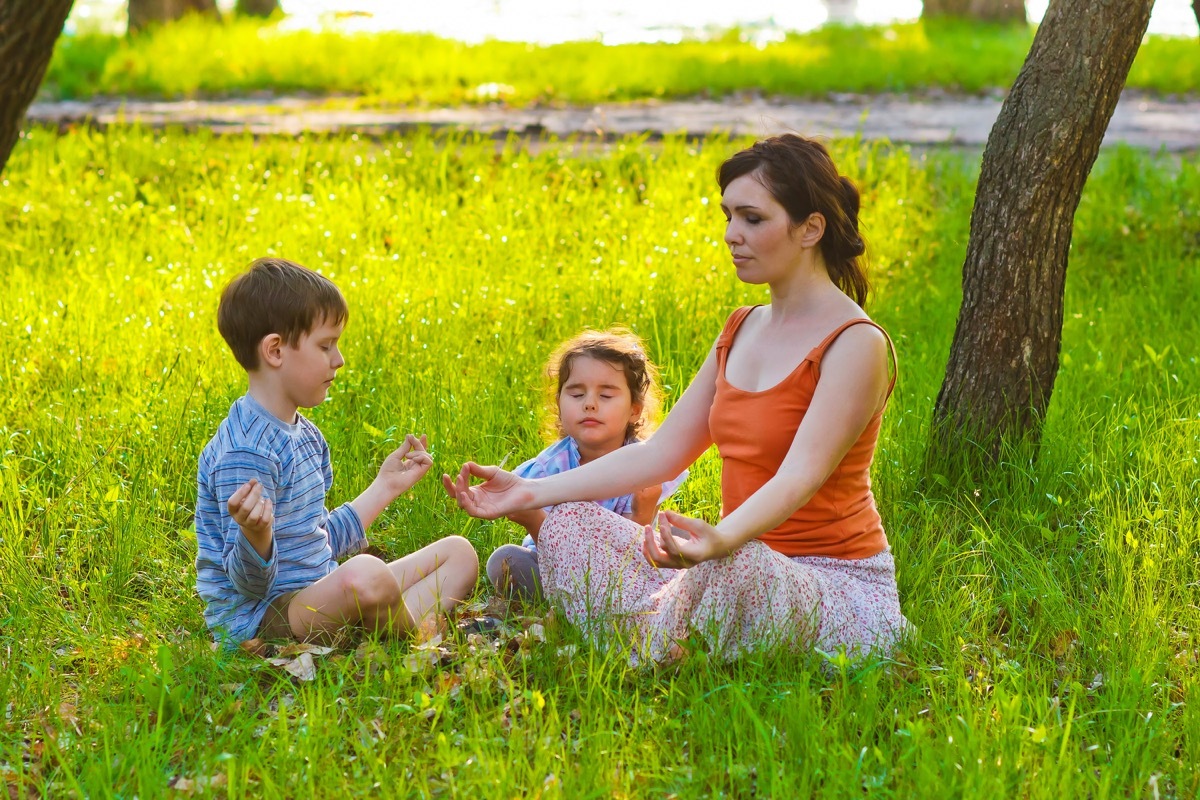 white mother and children meditating in grass