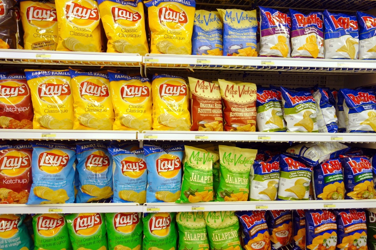 a chip aisle in the grocery store featuring junk food and snack food like lays and ruffles potato chips