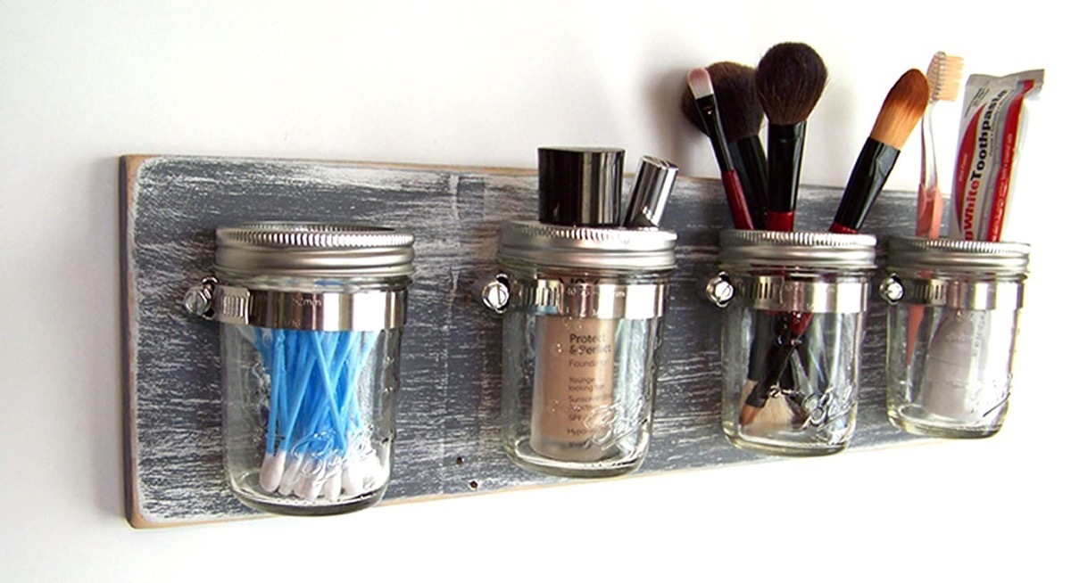 mason jars full of toiletry products and makeup on wooden board