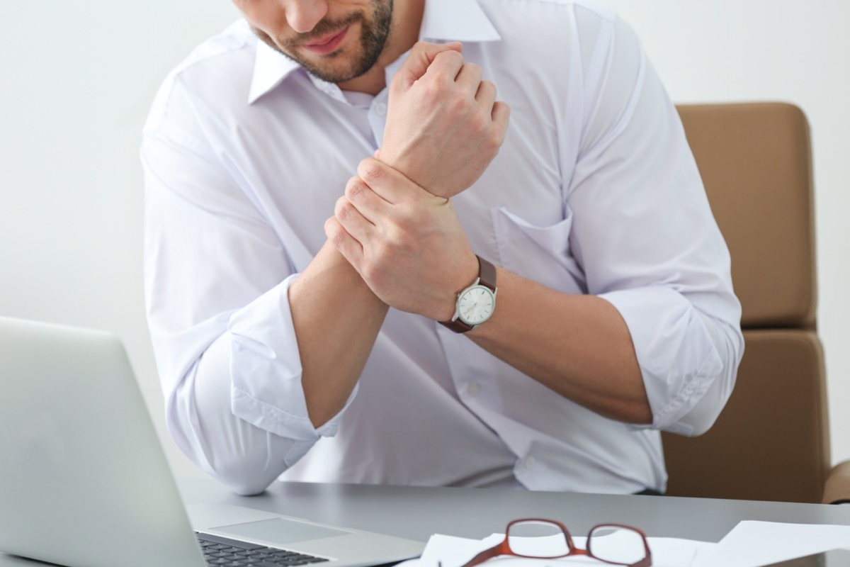 man suffering from wrist pain in office