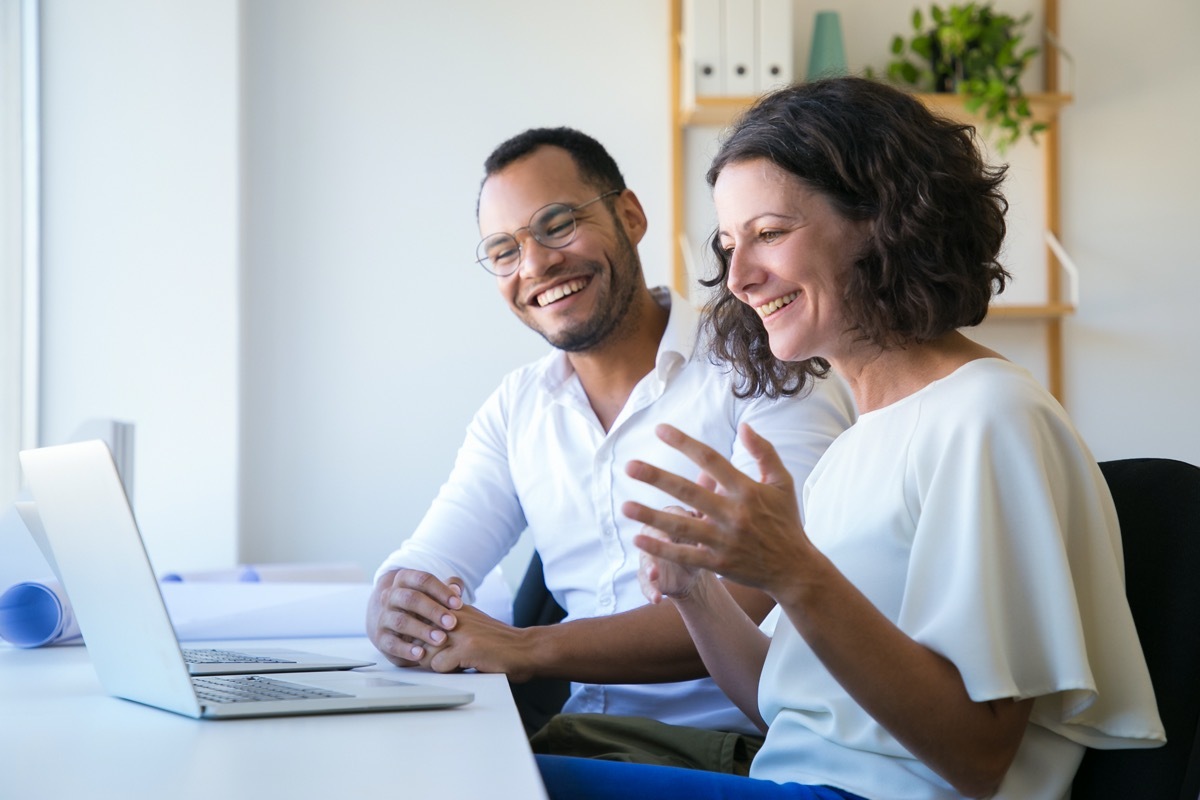 Cheerful colleagues using laptop for video call