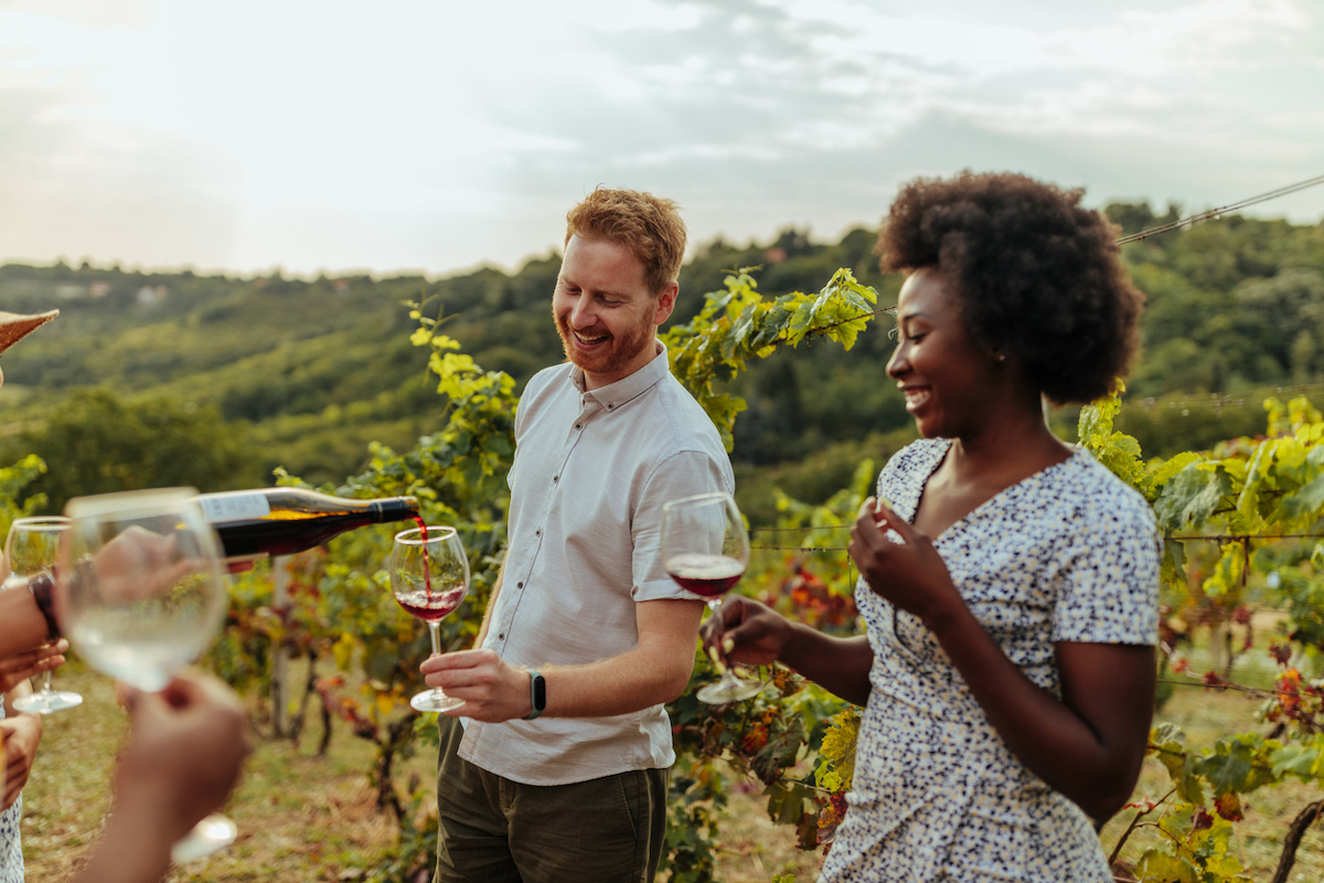 A couple enjoying a wine tasting in the middle of a vineyard.