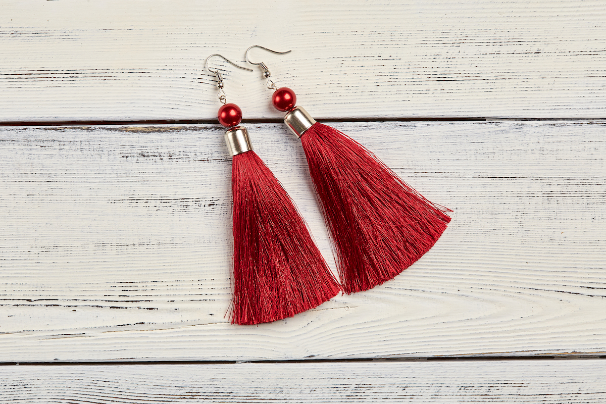 red tassel earrings on white wood background