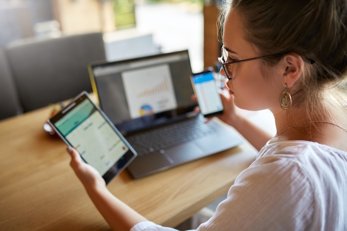 woman in glasses working with multiple electronic internet devices