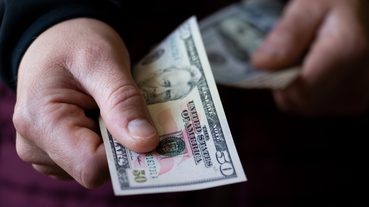 Fifty dollar bill in white male hand closeup