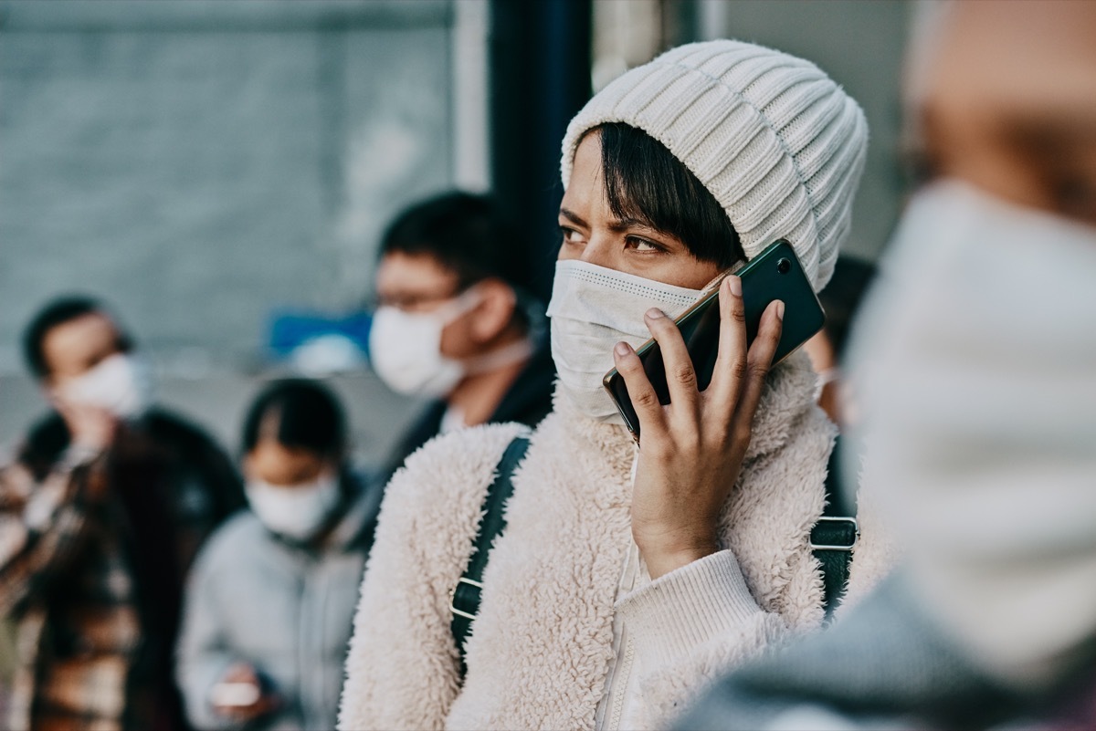 Shot of a young woman using a smartphone and wearing a mask while travelling in a foreign city