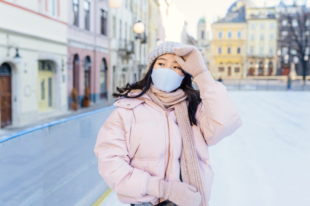 woman in winter clothing with face mask on ice skating rink