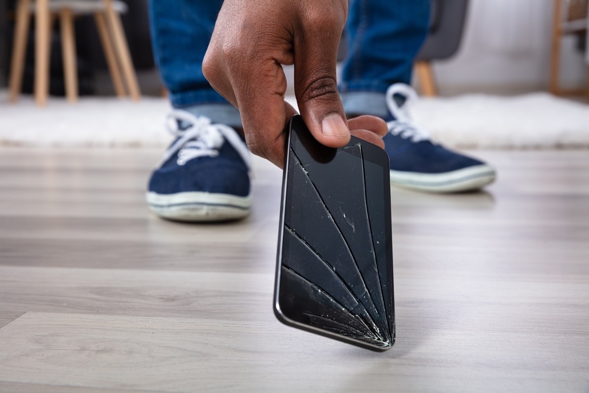 young black man picking up broken phone