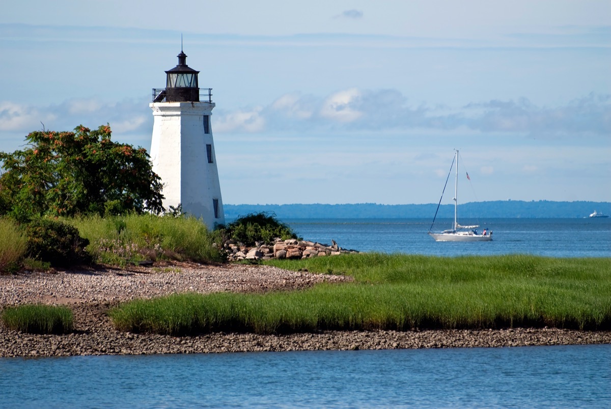 lighthouse with a sailboat behind it