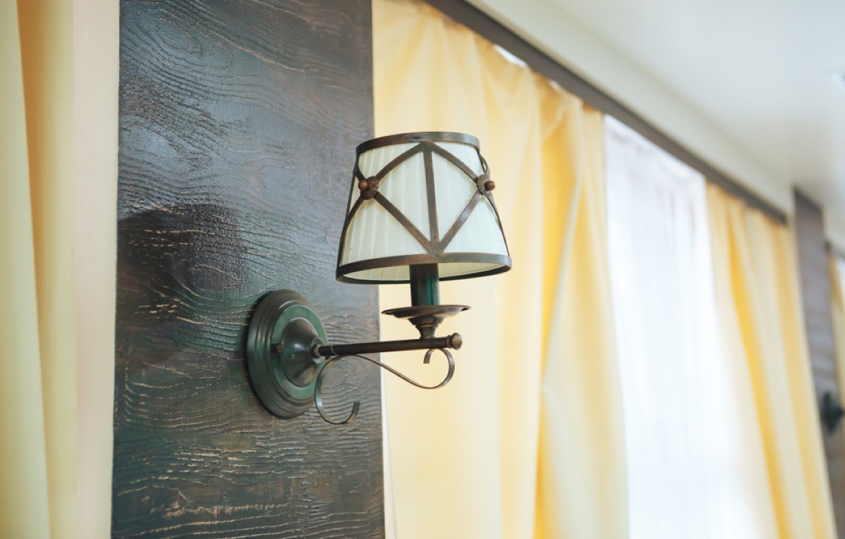 vintage inspired wall sconce next to window with yellow curtain