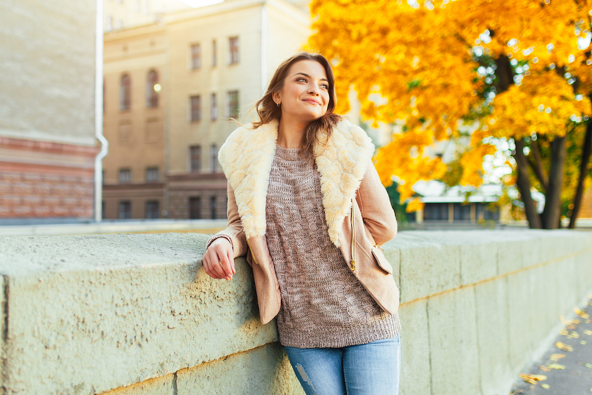 Young woman wearing a sweater and a shearling jacket on a fall day