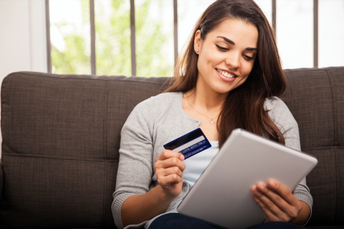 young woman smiling while holding tablet and credit card