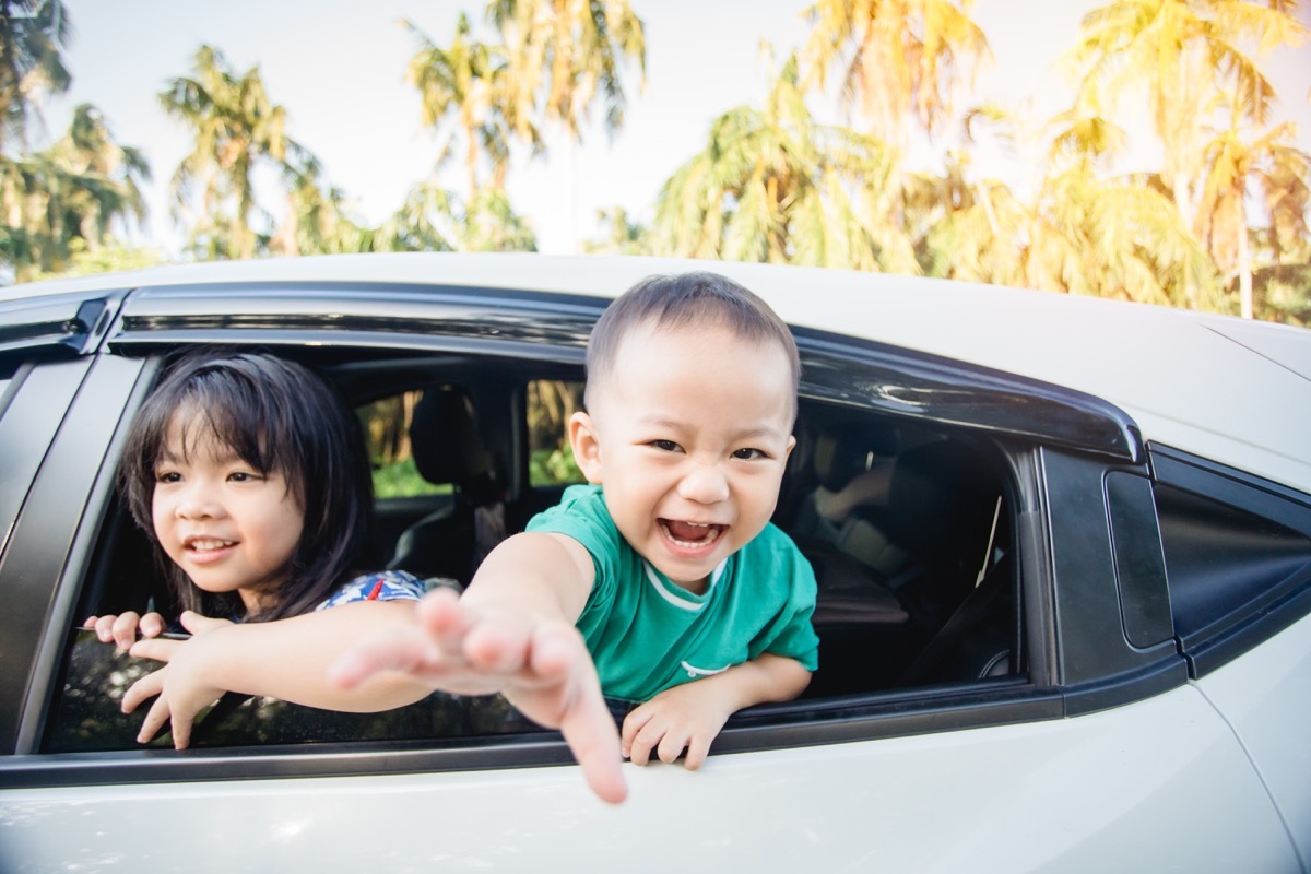 Asian kids laugh in backseat of car