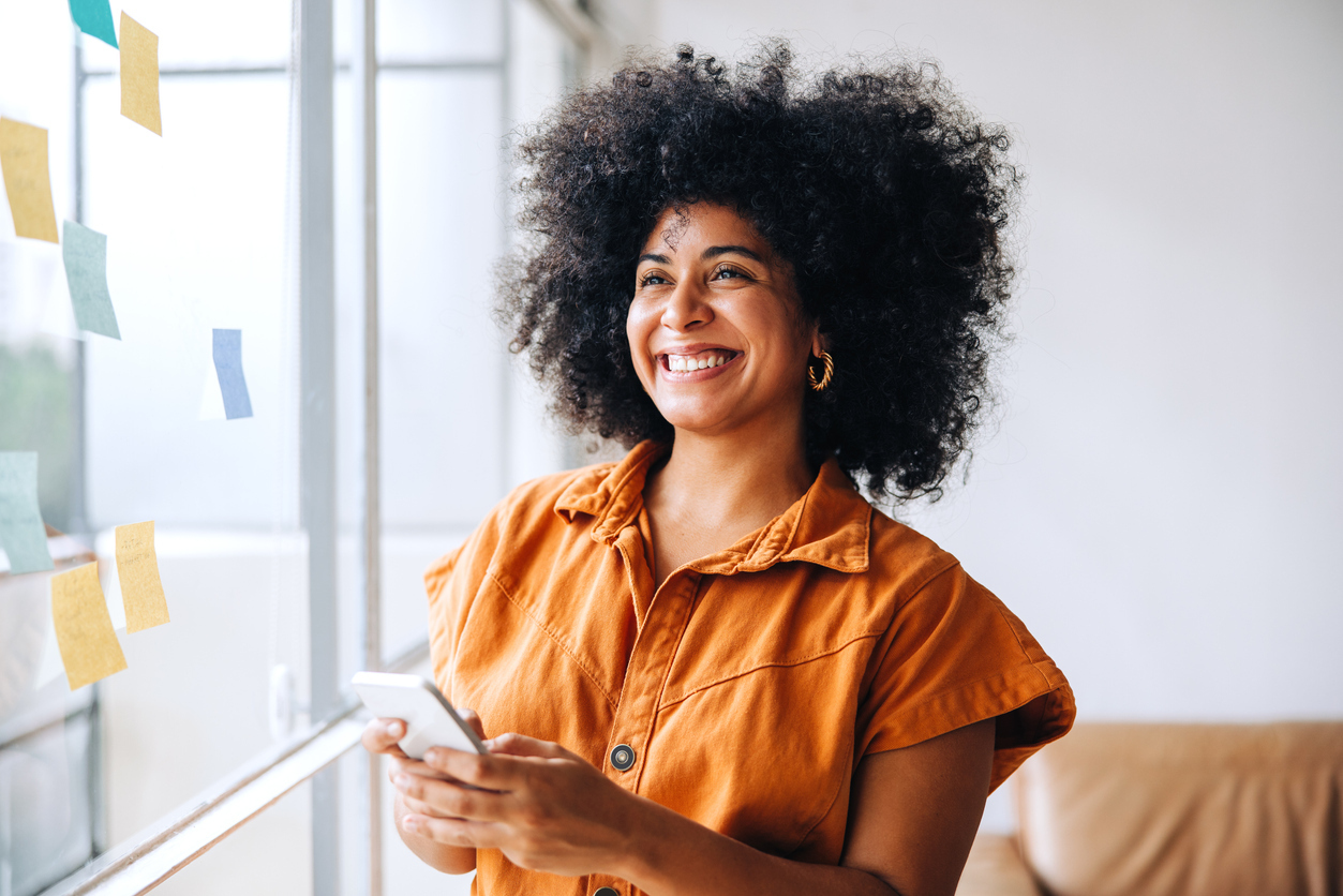 Happy black businesswoman smiling while using a smartphone