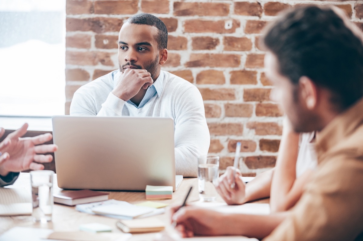 man sitting at a conference table listening to a work pitch