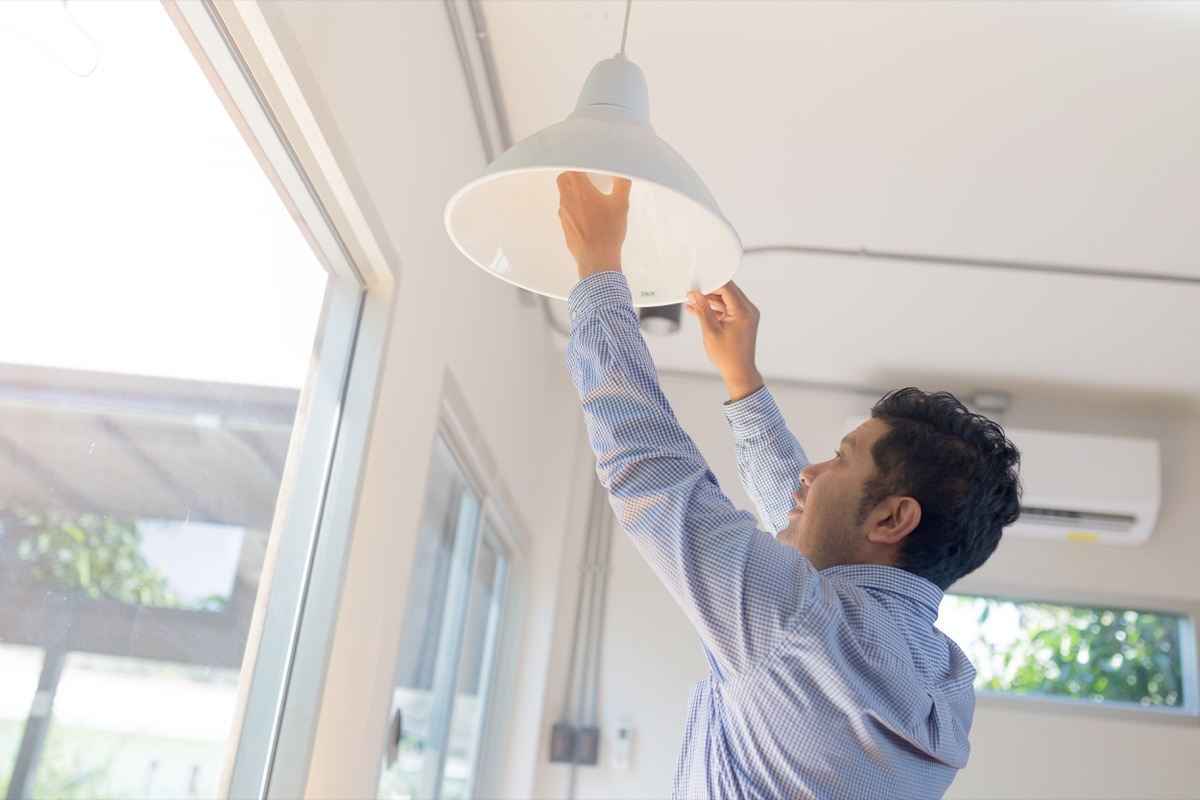 young asian man installing pendant lamp